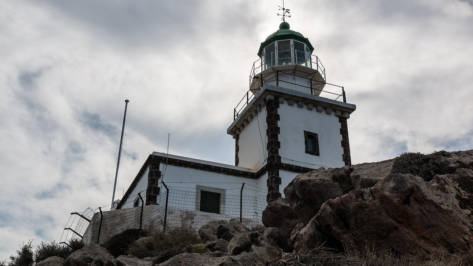 De witte vuurtoren van Akrotiri op de rotsen aan de zuidwestpunt van Santorini
