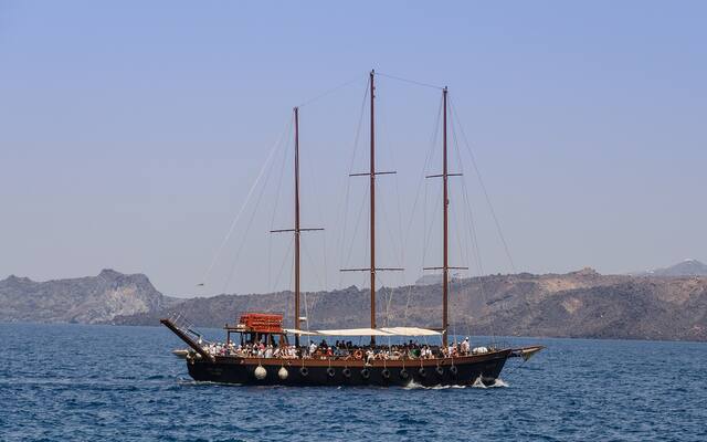 Rondvaartboot met twee masten in de caldera bij de haven van Athinios