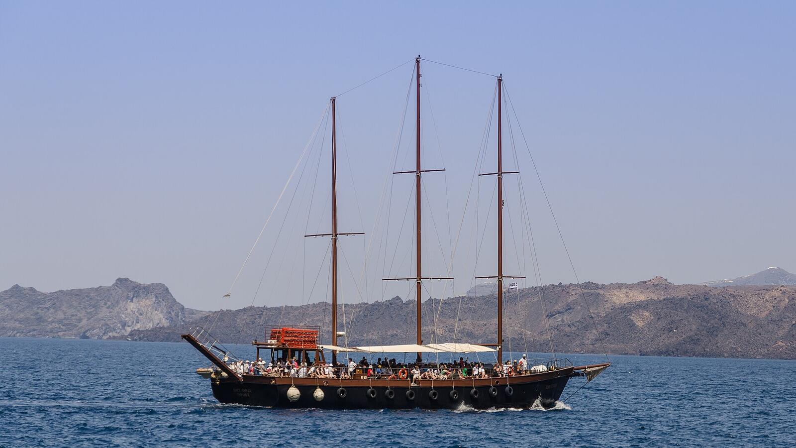 Rondvaartboot met twee masten in de caldera bij de haven van Athinios