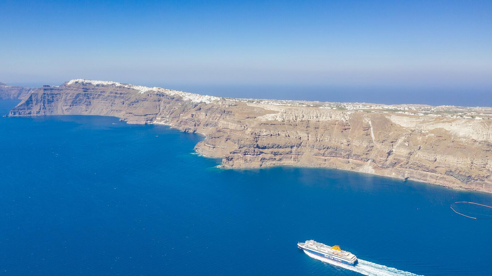 Een ferry vaart door de blauwe caldera van Santorini