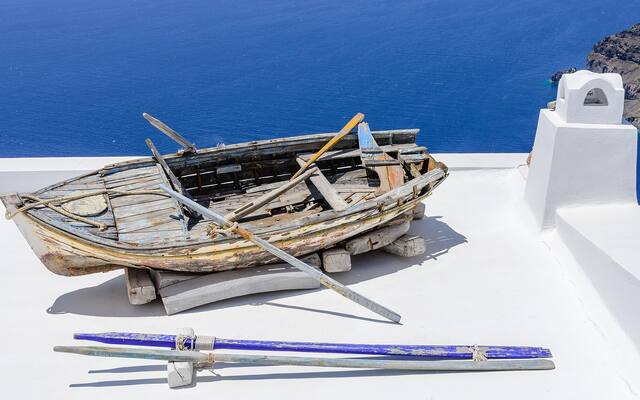 Een oude roeiboot als decoratie op een wit dak in Fira