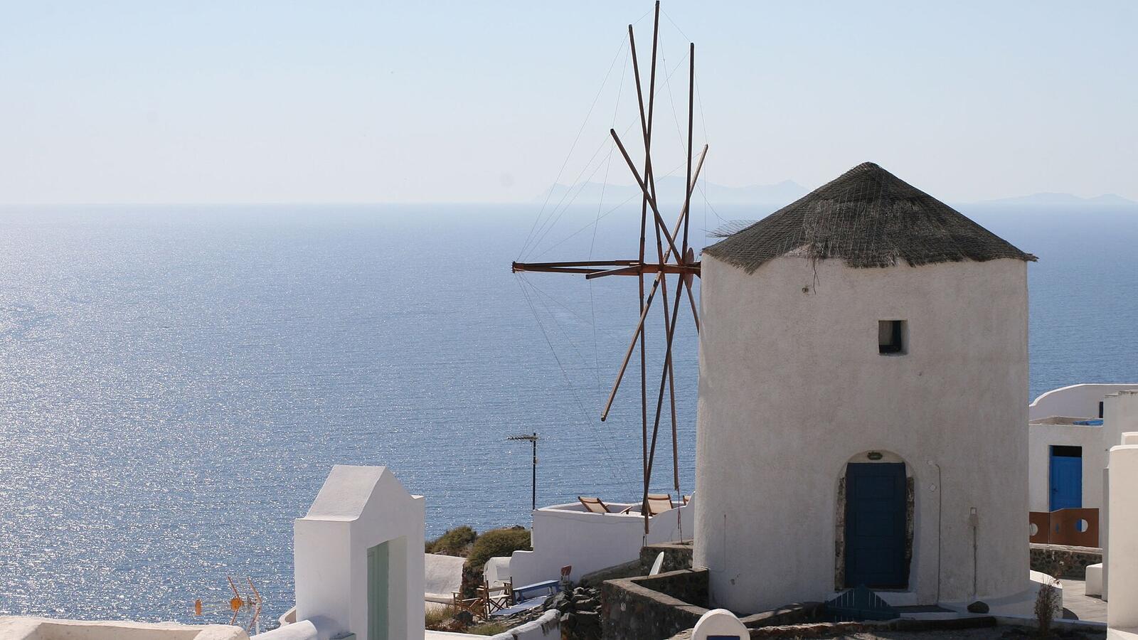 Een witte windmolen in Oia met de zee op de achtergrond
