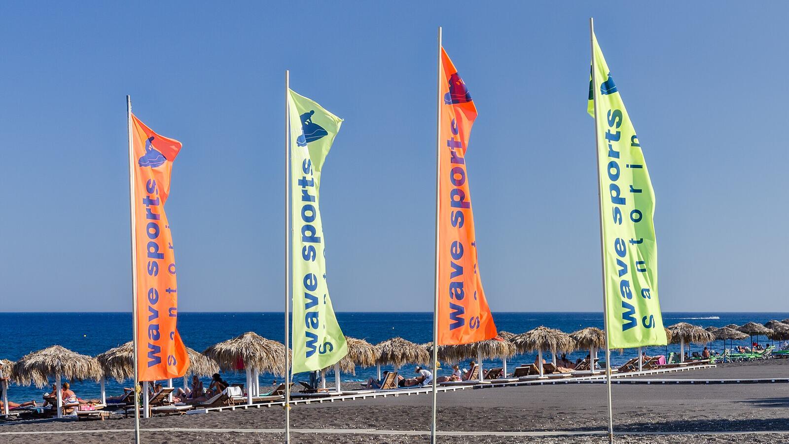 Kleurrijke watersportvlaggen op het zwarte strand van Perissa